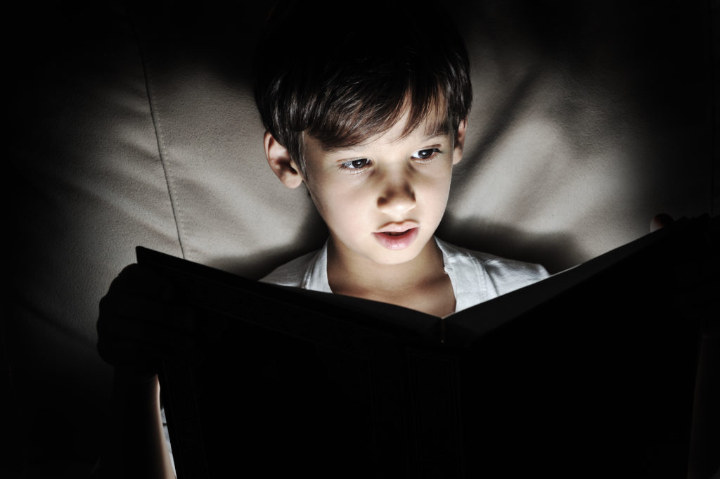 Kid reading book, light in darkness